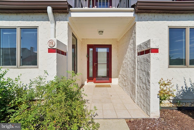 property entrance featuring a balcony and stucco siding