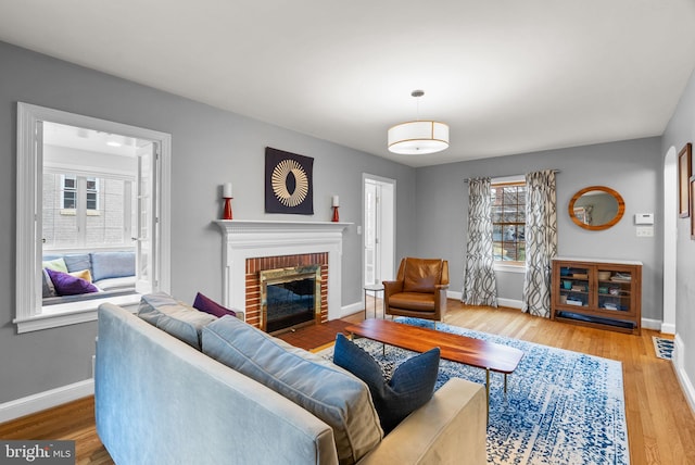 living room featuring a fireplace, baseboards, and wood finished floors