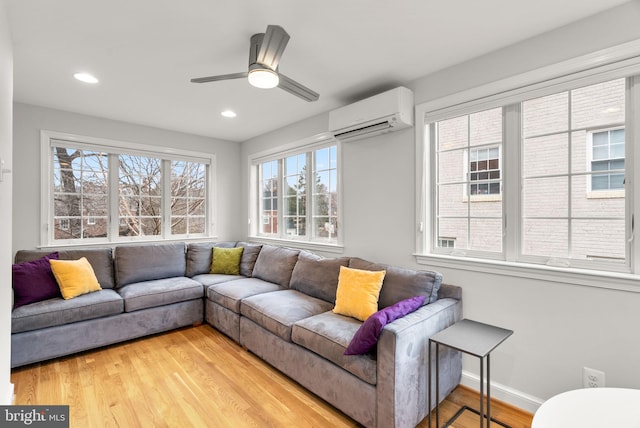 living room with recessed lighting, a ceiling fan, baseboards, an AC wall unit, and light wood-type flooring