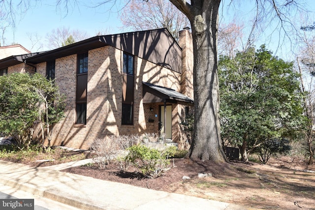 view of front of home with brick siding and a chimney