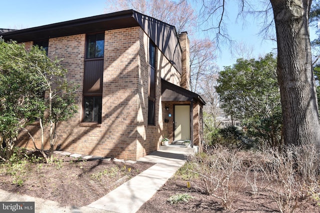 view of side of property with brick siding and a chimney