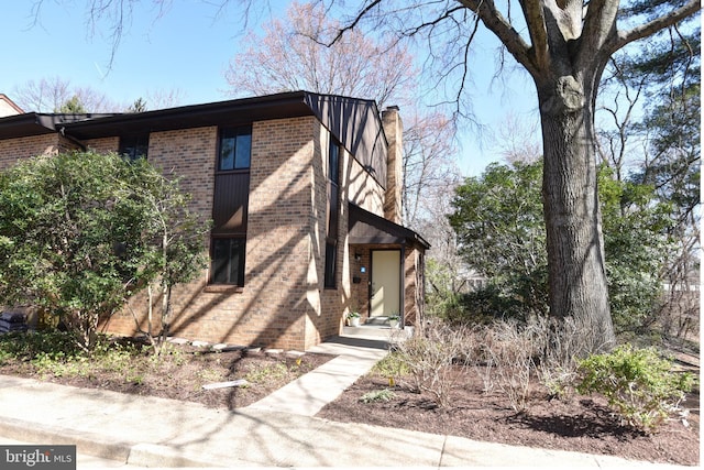 view of front facade featuring brick siding and a chimney