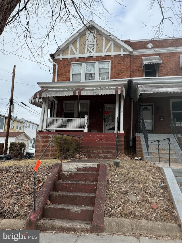 townhome / multi-family property featuring covered porch and brick siding