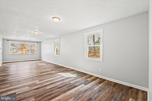 unfurnished room featuring a textured ceiling, baseboards, and wood finished floors