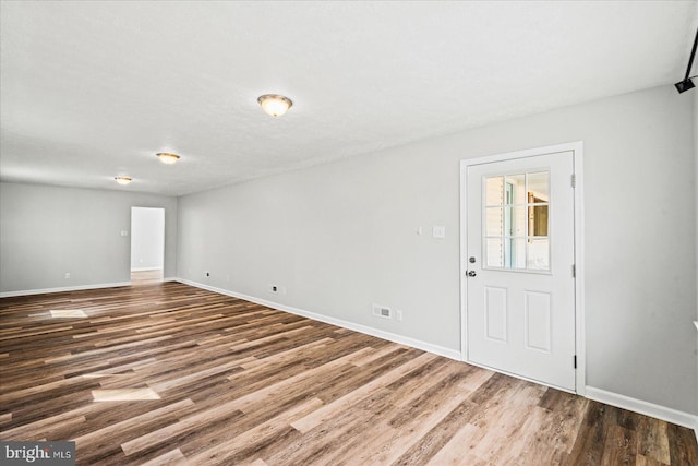 interior space featuring a textured ceiling, wood finished floors, and baseboards