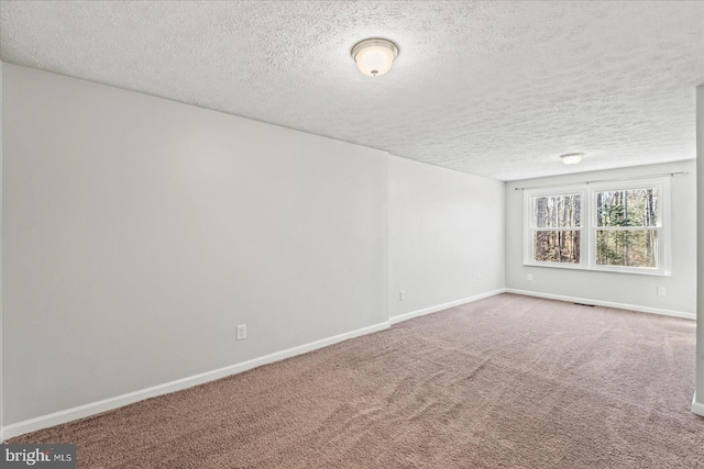 spare room with carpet, visible vents, baseboards, and a textured ceiling