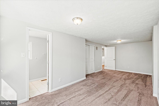 interior space with carpet, visible vents, a textured ceiling, and baseboards