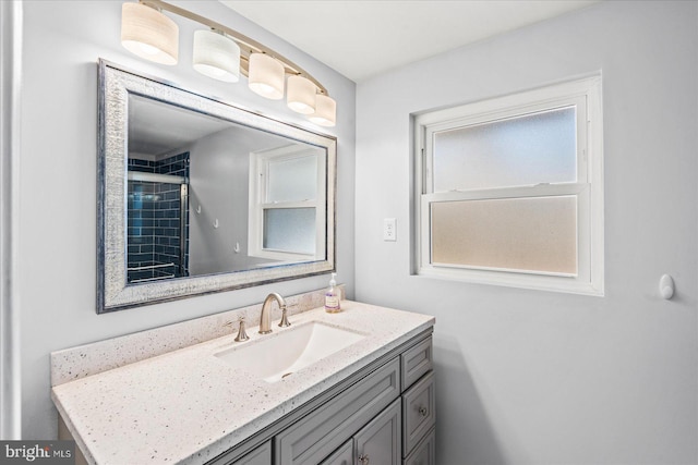 bathroom with a tile shower and vanity