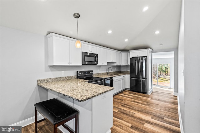 kitchen with white cabinets, wood finished floors, light stone countertops, black appliances, and a sink