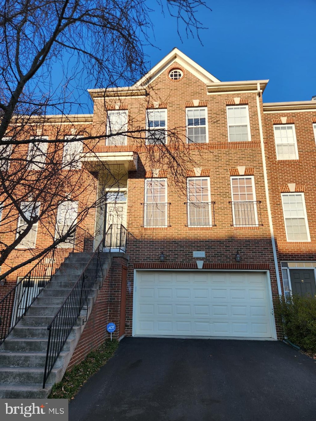 multi unit property with a garage, aphalt driveway, and brick siding