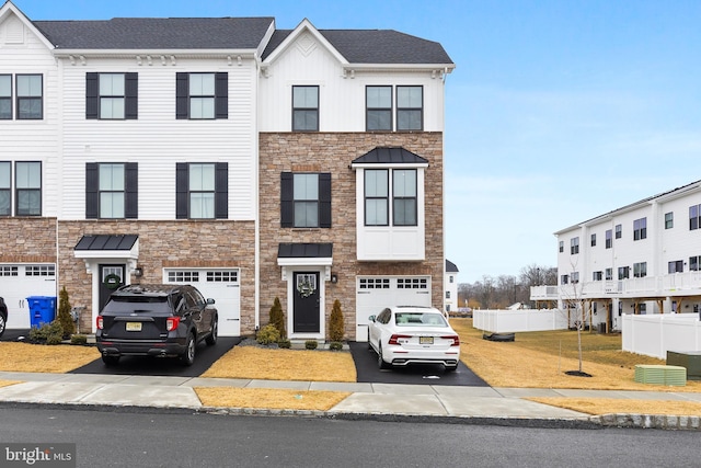 view of property featuring board and batten siding, stone siding, driveway, and an attached garage