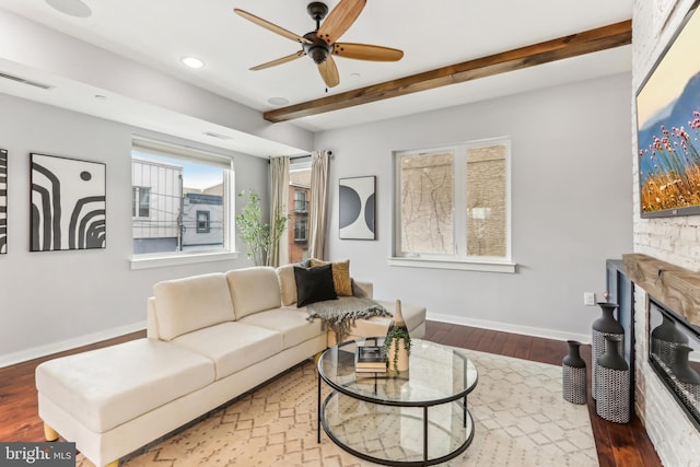 living area with visible vents, beamed ceiling, baseboards, and wood finished floors