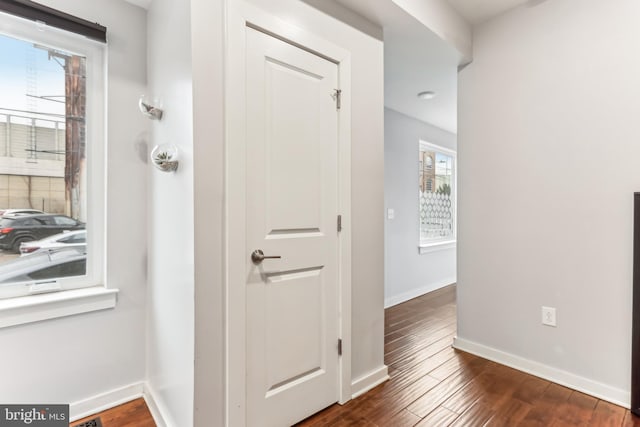 hallway with baseboards and dark wood-type flooring