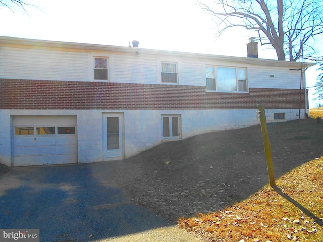 exterior space featuring a garage, brick siding, and a chimney