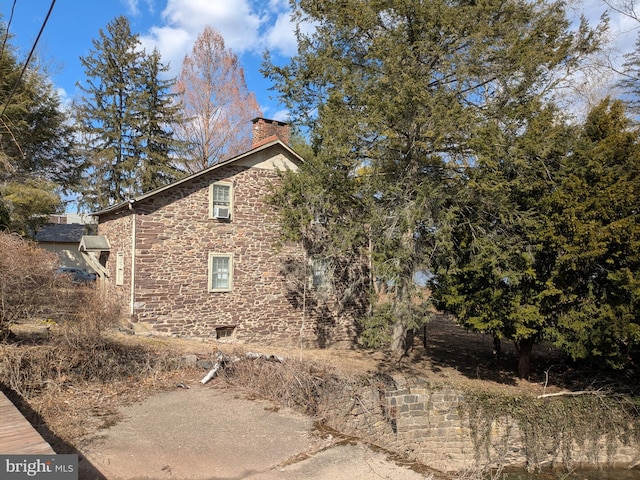 view of property exterior with stone siding and a chimney