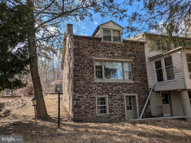 exterior space featuring stone siding and a chimney