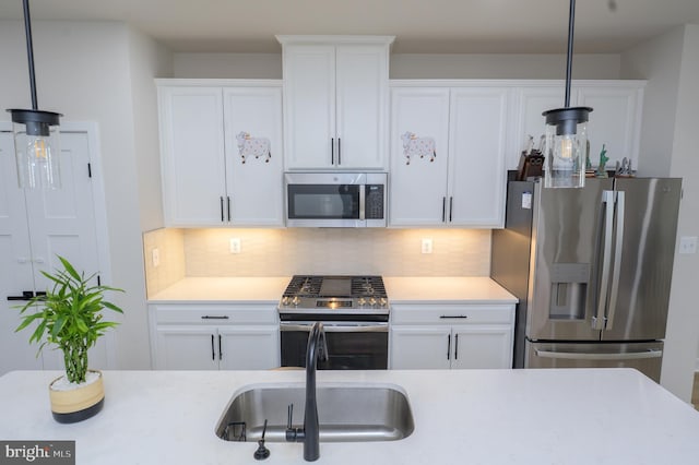 kitchen featuring white cabinets, stainless steel appliances, light countertops, pendant lighting, and backsplash