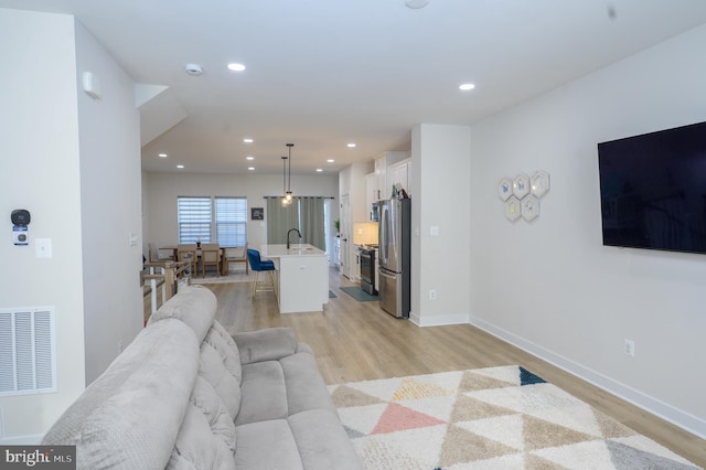 living area featuring baseboards, recessed lighting, visible vents, and light wood-style floors