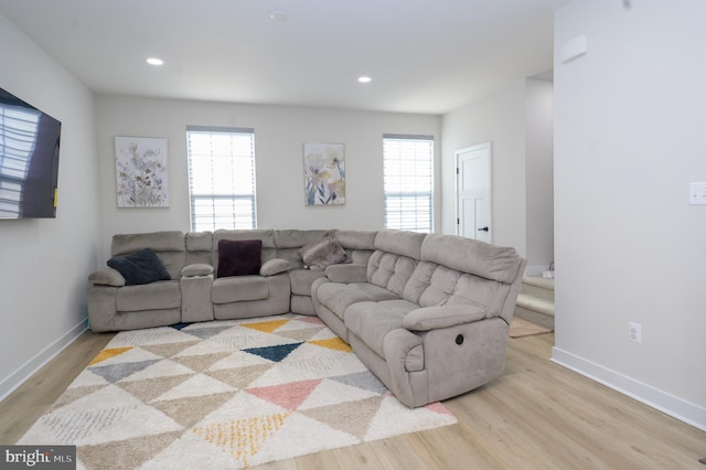 living area with light wood-style floors, baseboards, and a wealth of natural light