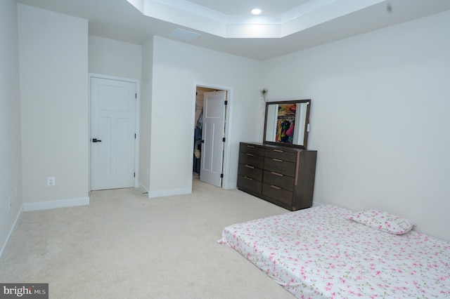 bedroom with light colored carpet, visible vents, baseboards, a spacious closet, and a raised ceiling