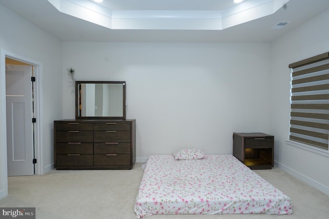 bedroom featuring baseboards, visible vents, a tray ceiling, and light colored carpet