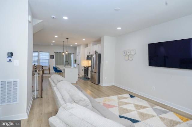 living area with light wood-type flooring, baseboards, visible vents, and recessed lighting