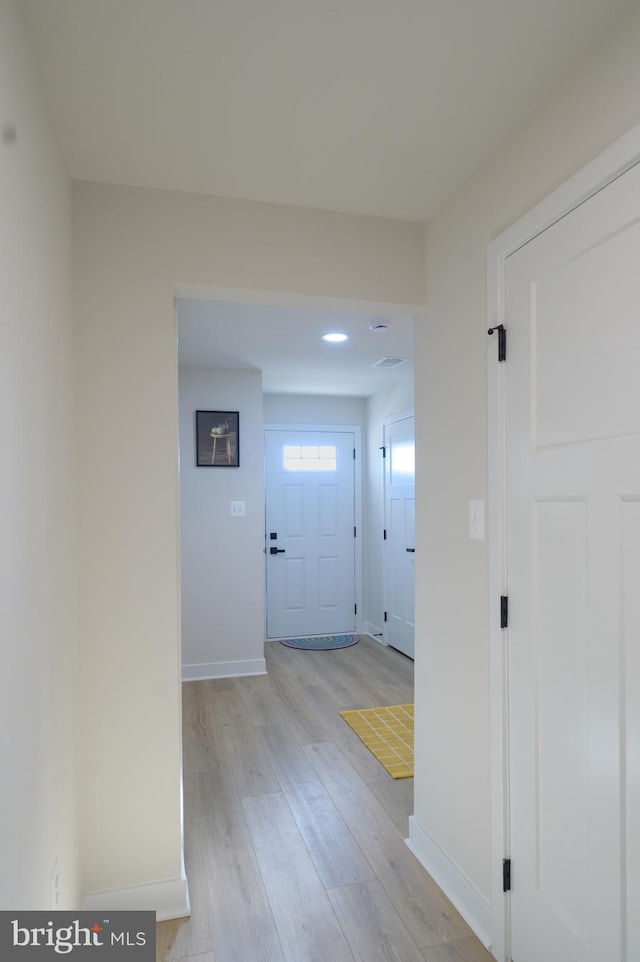 hall featuring light wood-style floors and baseboards