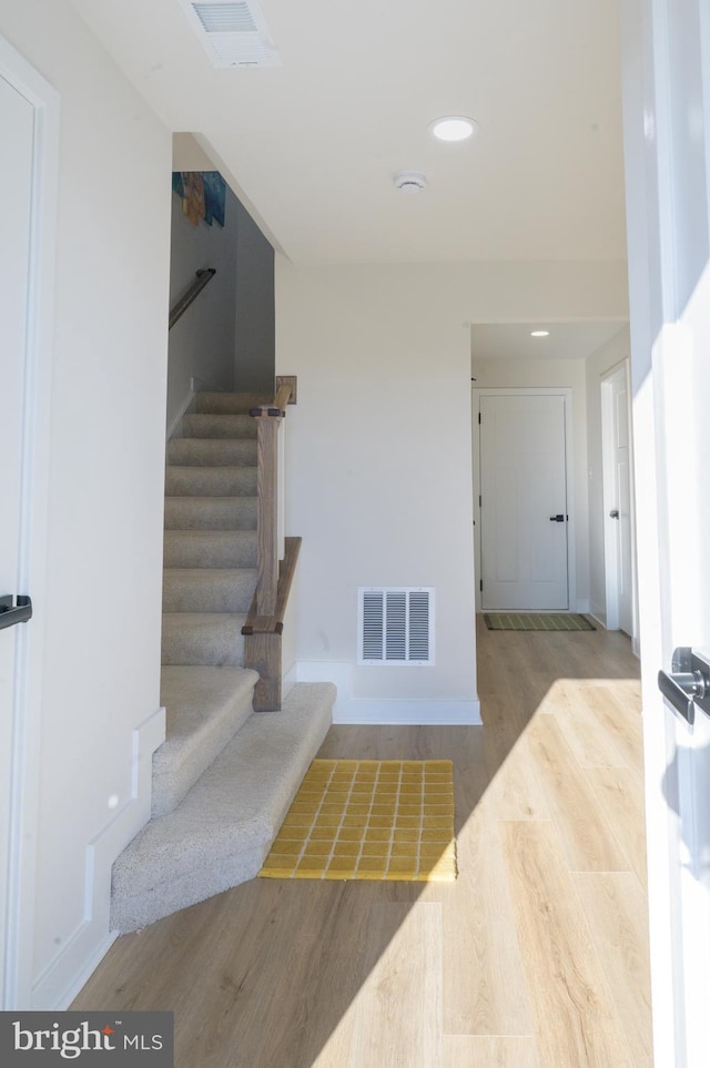 staircase featuring baseboards, visible vents, wood finished floors, and recessed lighting