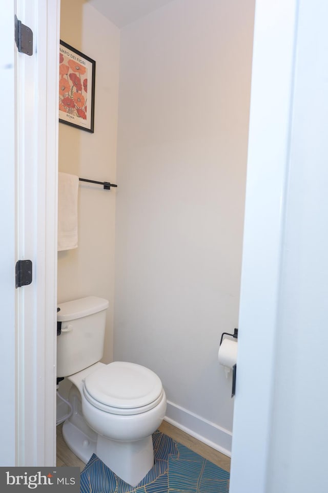 bathroom with wood finished floors, toilet, and baseboards