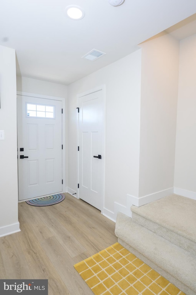 foyer entrance with stairs, wood finished floors, visible vents, and baseboards