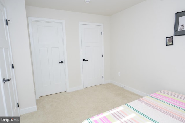 bedroom with light carpet and baseboards