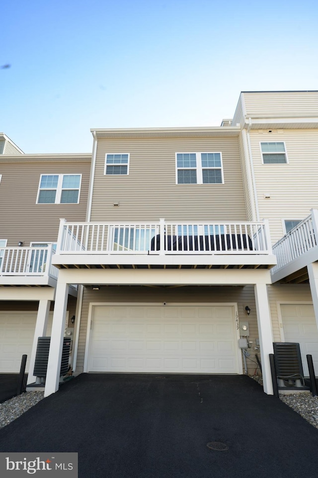 townhome / multi-family property with driveway, a balcony, and an attached garage