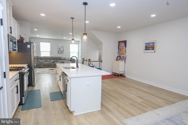 kitchen featuring stainless steel appliances, an island with sink, light countertops, and white cabinetry