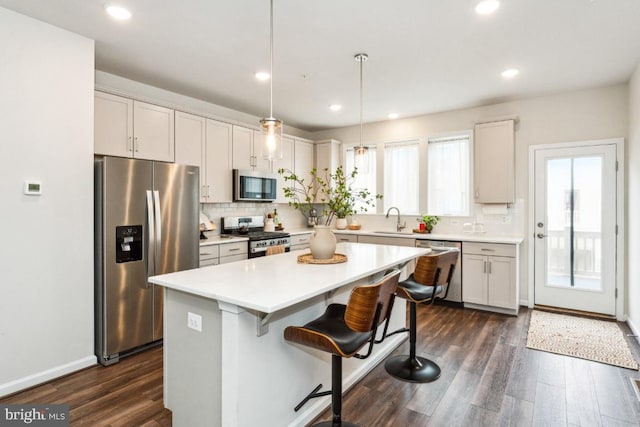 kitchen with backsplash, dark wood-style flooring, stainless steel appliances, and a sink