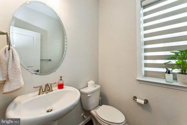 bathroom with baseboards, a sink, and toilet