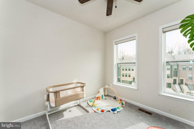 recreation room featuring a ceiling fan, carpet, visible vents, and baseboards