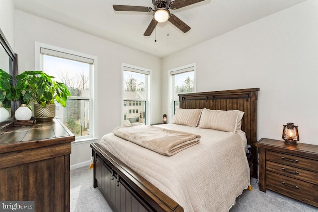 bedroom featuring light carpet, a ceiling fan, and baseboards