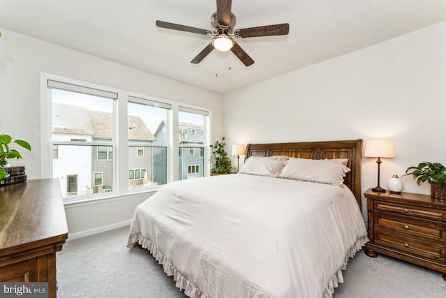 bedroom with a ceiling fan, light colored carpet, and baseboards