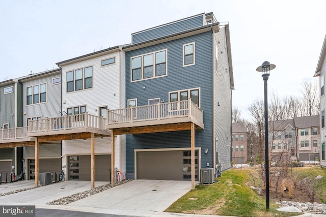 rear view of property with an attached garage, driveway, and central AC