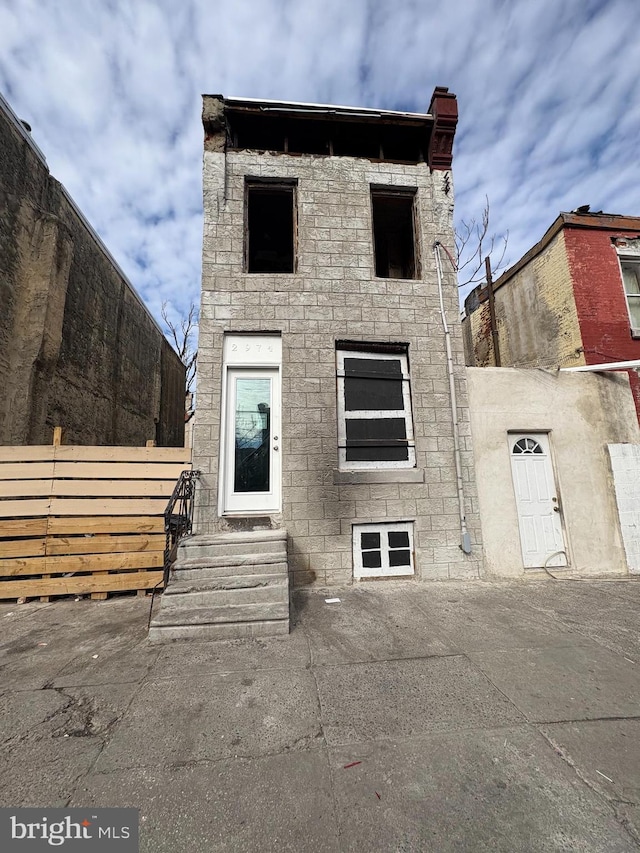 view of front facade with entry steps, stone siding, and fence