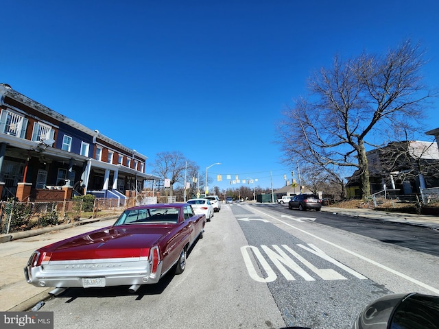 view of road featuring street lights, curbs, sidewalks, and a residential view