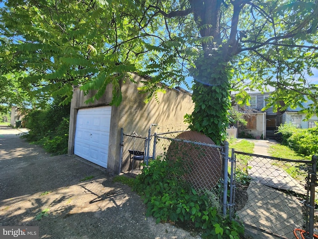 2030 N Washington St, Baltimore, MD 21213 - detached garage featuring a gate, asphalt driveway, and fence
