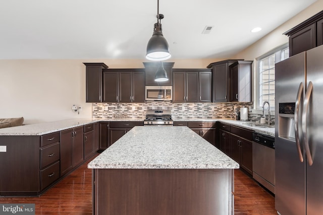 kitchen with a sink, visible vents, appliances with stainless steel finishes, a center island, and pendant lighting