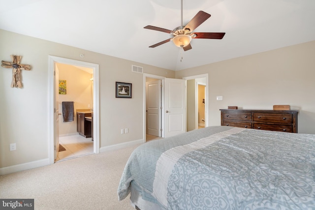 bedroom with light colored carpet, a ceiling fan, baseboards, visible vents, and ensuite bath