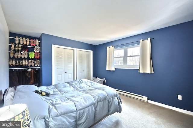 bedroom with a baseboard heating unit, carpet, baseboards, and multiple closets