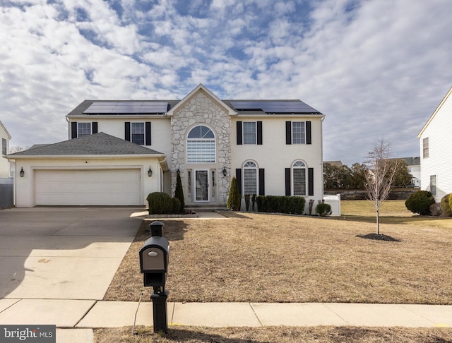 view of front of home featuring a garage, driveway, stone siding, and roof mounted solar panels