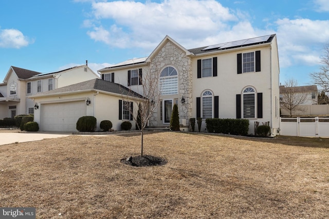 view of front of house with solar panels, fence, a garage, driveway, and a front lawn