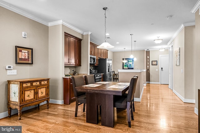 dining room featuring light wood-style floors, baseboards, and crown molding