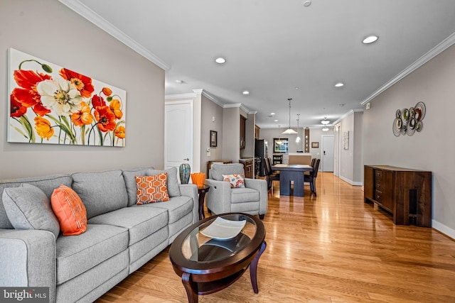 living room featuring baseboards, crown molding, recessed lighting, and light wood-style floors