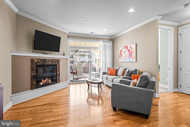 living room with baseboards, ornamental molding, wood finished floors, and a high end fireplace